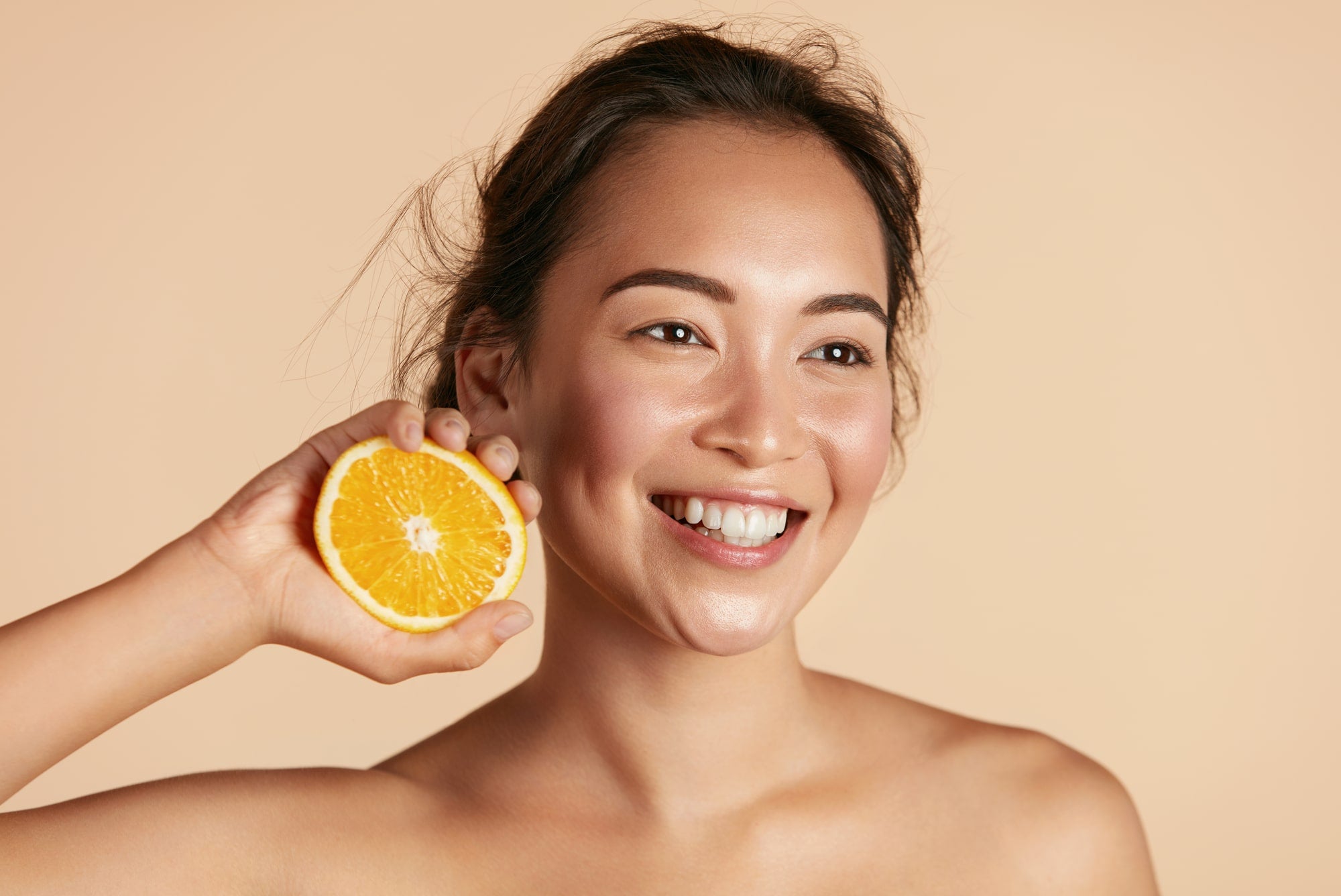 Vitamin C skin benefits. Woman holding orange.